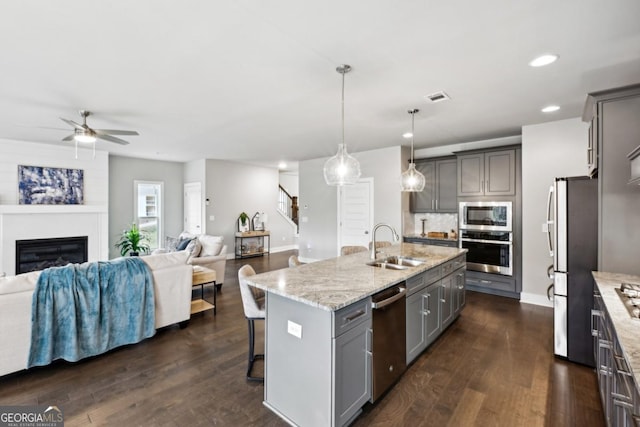 kitchen featuring open floor plan, gray cabinets, appliances with stainless steel finishes, and a sink