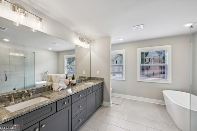 bathroom with double vanity, a freestanding tub, a stall shower, and a sink