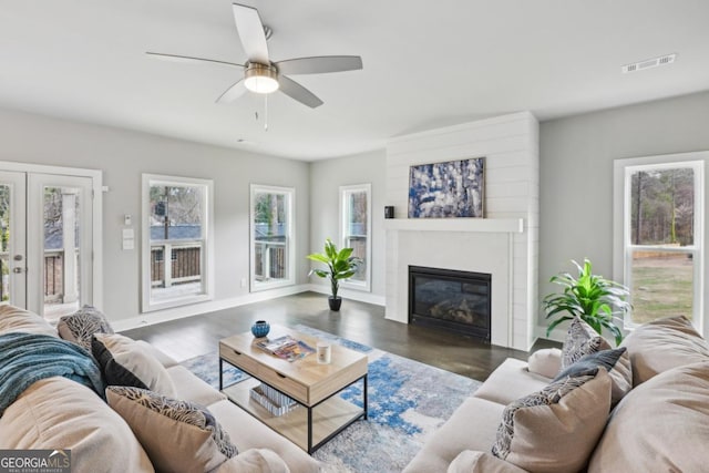 living room featuring a glass covered fireplace, french doors, visible vents, and baseboards