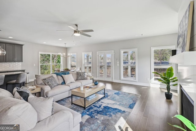 living area with ceiling fan with notable chandelier, dark wood-type flooring, recessed lighting, and baseboards