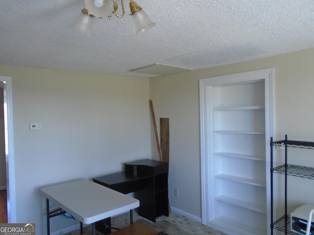 office with built in shelves and a textured ceiling