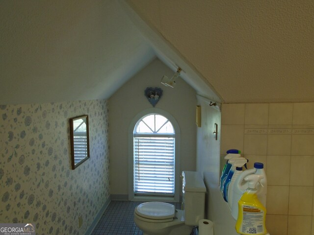 bathroom featuring tile patterned flooring, toilet, wallpapered walls, and vaulted ceiling