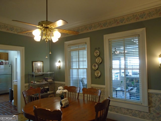 dining area featuring a wainscoted wall, ornamental molding, and a ceiling fan