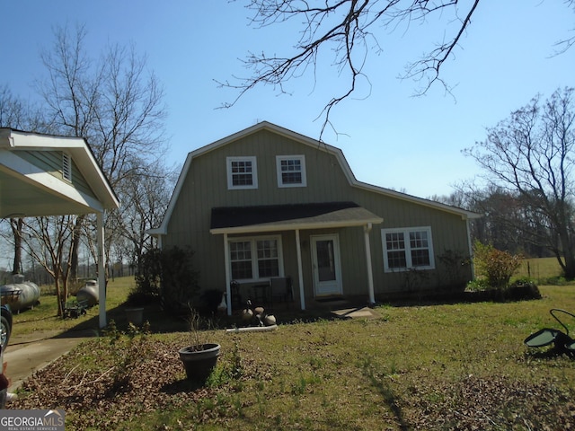 view of front facade with a front yard, covered porch, and a gambrel roof