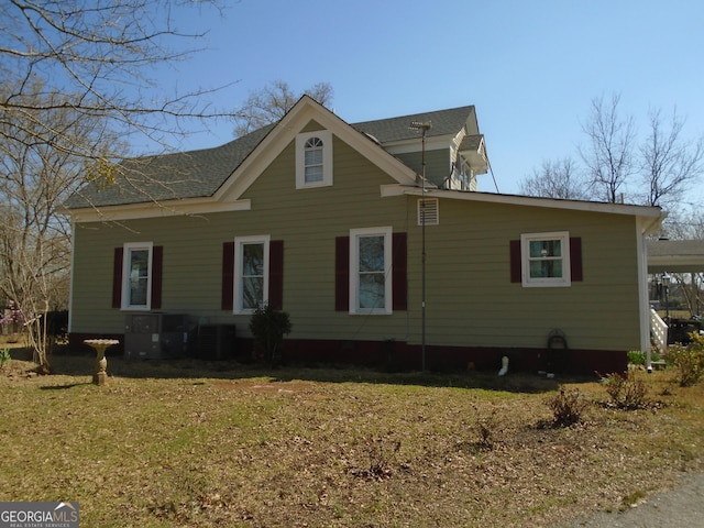 view of property exterior featuring central AC unit, a lawn, and roof with shingles