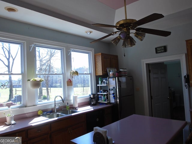 kitchen featuring brown cabinets, freestanding refrigerator, and a sink