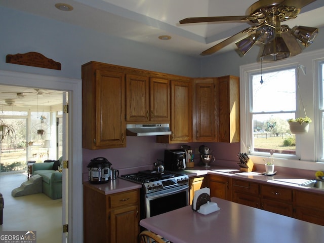 kitchen featuring light countertops, brown cabinetry, stainless steel gas stove, and under cabinet range hood