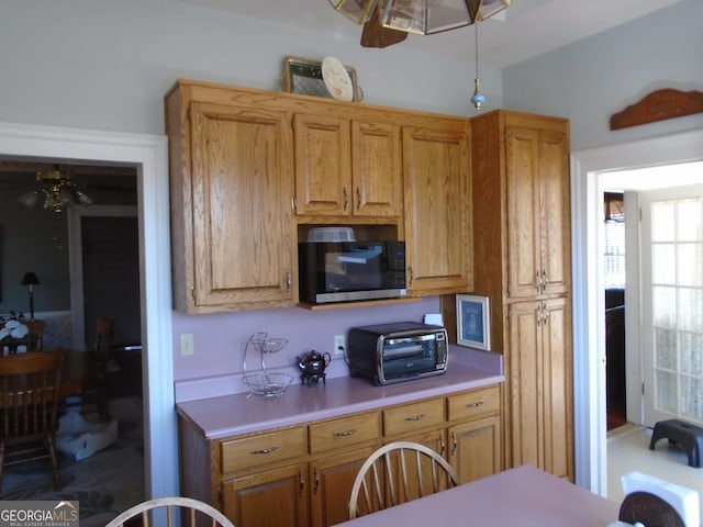 kitchen with a toaster, brown cabinetry, and light countertops