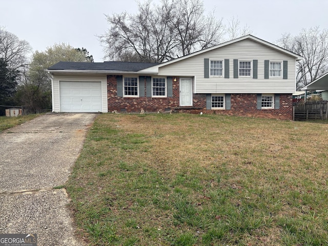 split level home featuring brick siding, a front yard, a garage, and fence