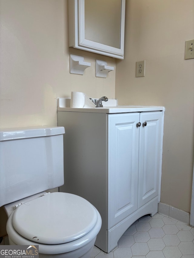 half bath with baseboards, toilet, and vanity