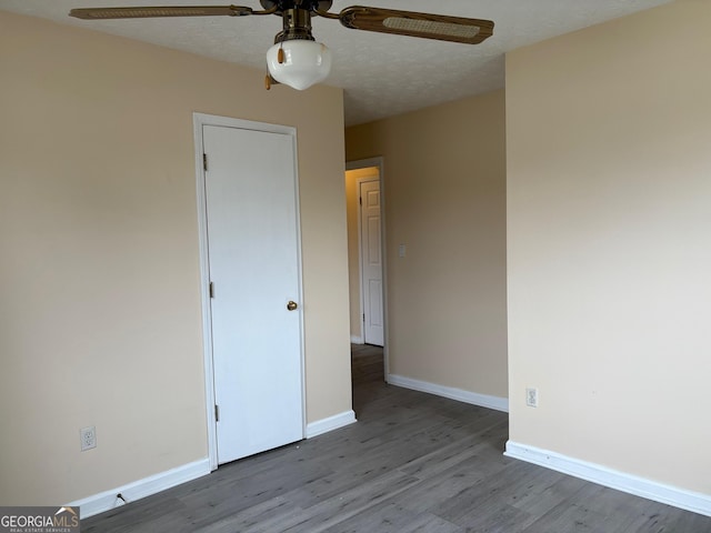 unfurnished bedroom with baseboards, a textured ceiling, wood finished floors, and a ceiling fan