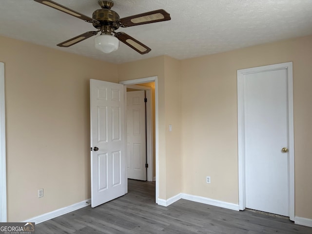 unfurnished bedroom with ceiling fan, wood finished floors, baseboards, and a textured ceiling