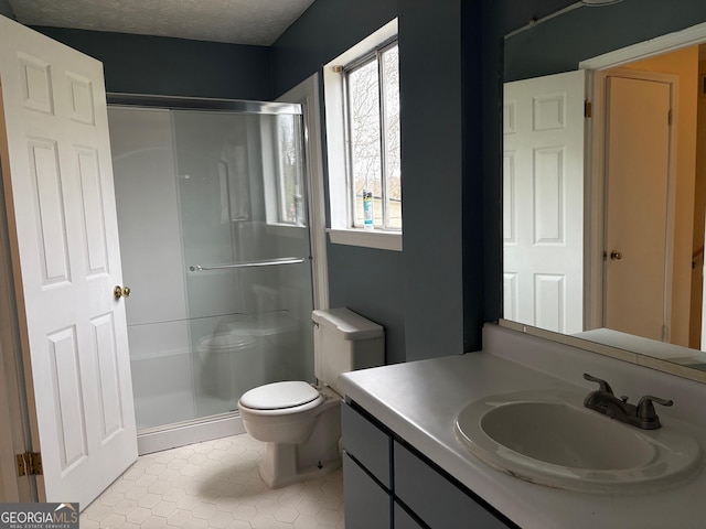 full bathroom with vanity, toilet, a stall shower, and a textured ceiling