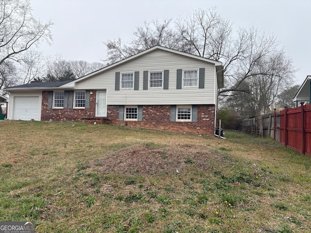 split level home with a garage, brick siding, a front yard, and fence