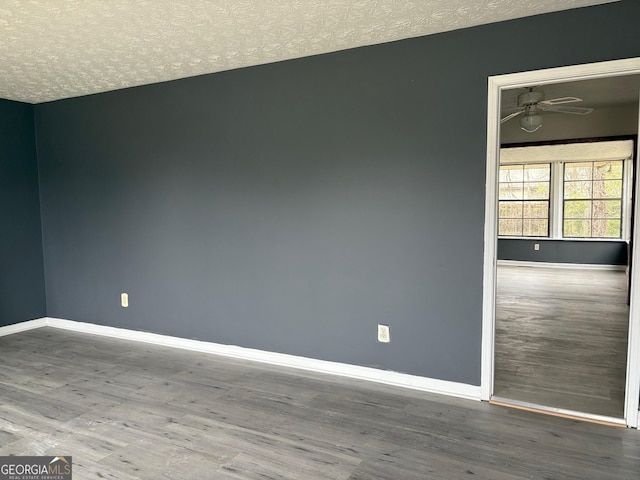 spare room featuring wood finished floors, a ceiling fan, baseboards, and a textured ceiling