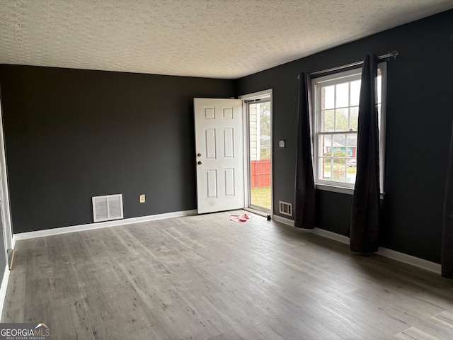 unfurnished bedroom with wood finished floors, visible vents, and baseboards