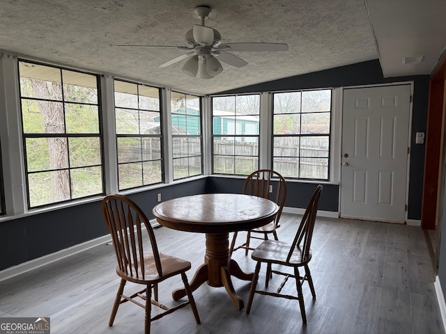 dining area featuring visible vents, baseboards, vaulted ceiling, wood finished floors, and a ceiling fan