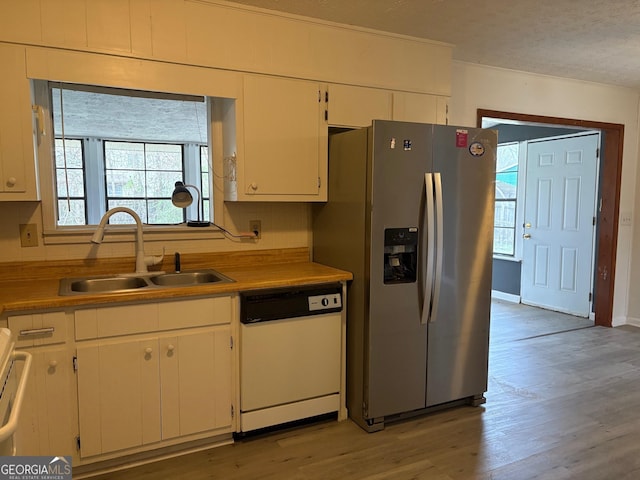 kitchen featuring a sink, stainless steel fridge, light wood-style floors, white cabinets, and dishwasher