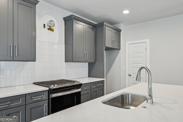 kitchen featuring gas stove, gray cabinets, and a sink