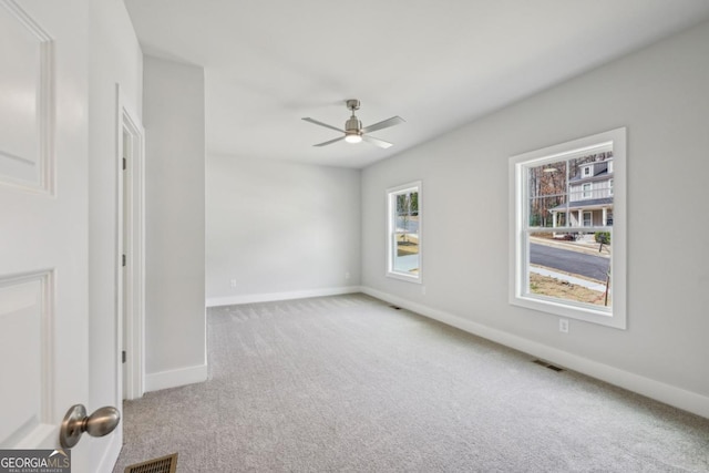 carpeted spare room with visible vents, ceiling fan, and baseboards