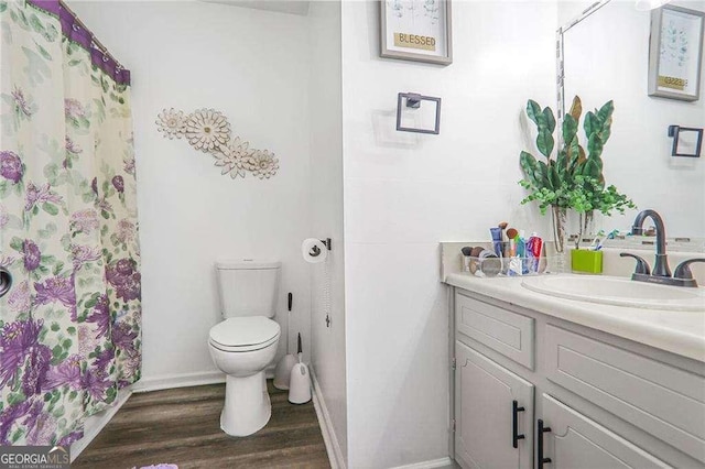 bathroom with vanity, wood finished floors, baseboards, curtained shower, and toilet