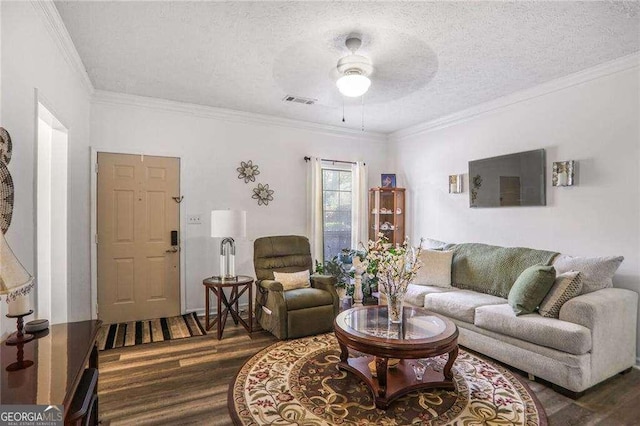 living room with wood finished floors, a textured ceiling, visible vents, and ornamental molding