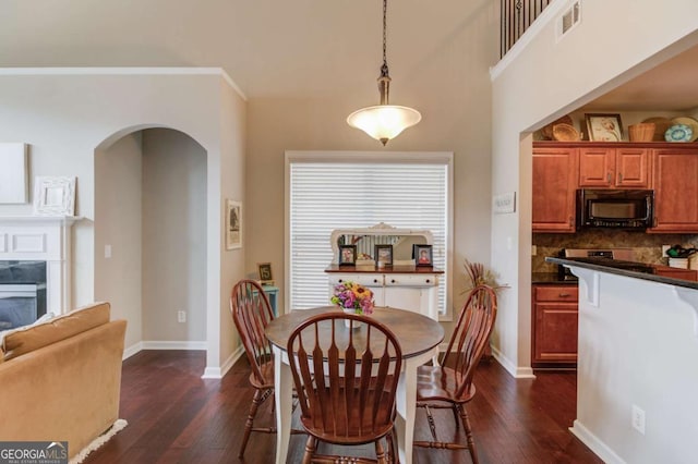 dining space featuring dark wood finished floors, arched walkways, and baseboards