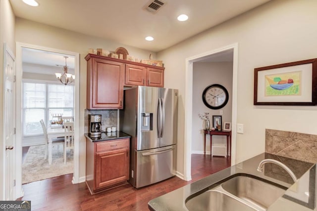 kitchen with dark countertops, visible vents, dark wood-type flooring, stainless steel fridge with ice dispenser, and a sink