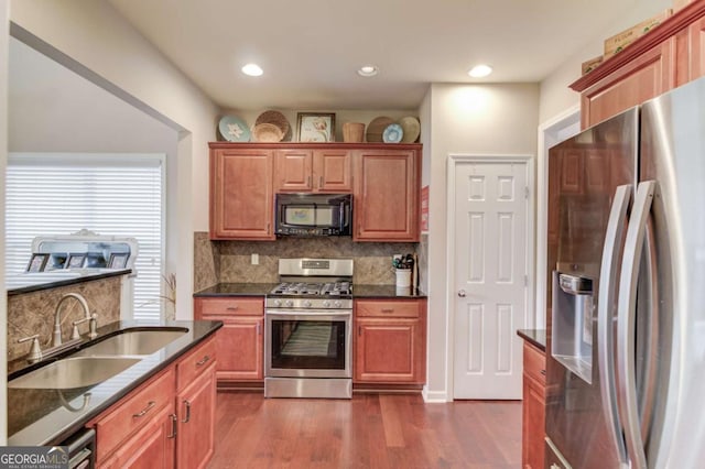 kitchen featuring a sink, decorative backsplash, dark wood-type flooring, appliances with stainless steel finishes, and brown cabinets