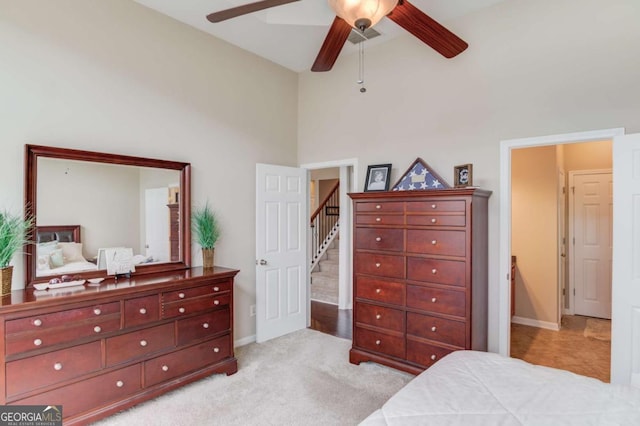 bedroom featuring light colored carpet, a high ceiling, and baseboards