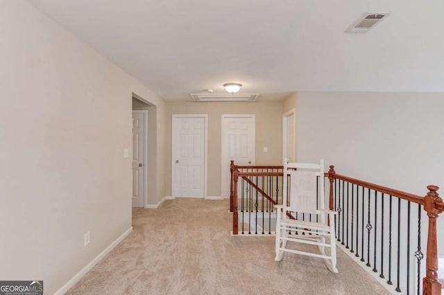 hallway featuring carpet, visible vents, baseboards, attic access, and an upstairs landing