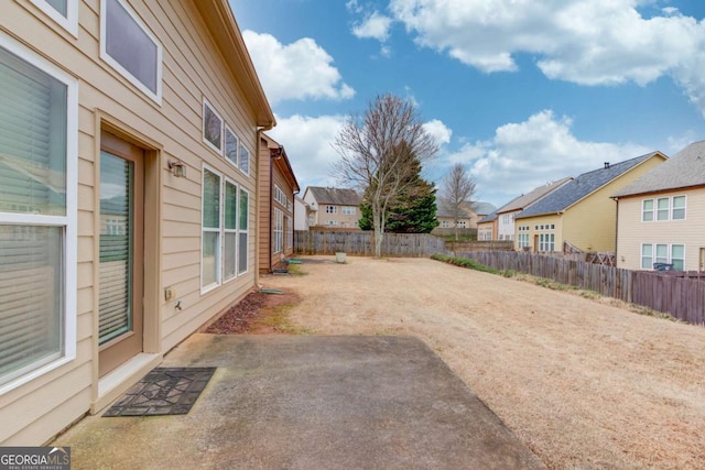 view of yard with a patio, a fenced backyard, and a residential view