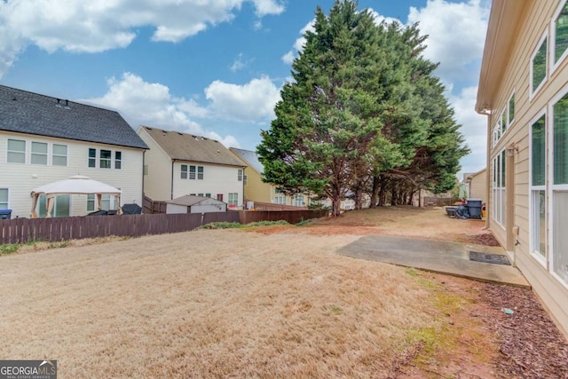 view of yard featuring a patio, fence, and a residential view