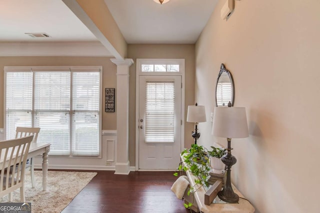 entrance foyer with visible vents, dark wood-type flooring, and ornate columns