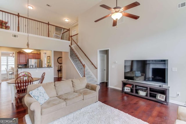 living room with visible vents, stairs, a ceiling fan, and wood finished floors