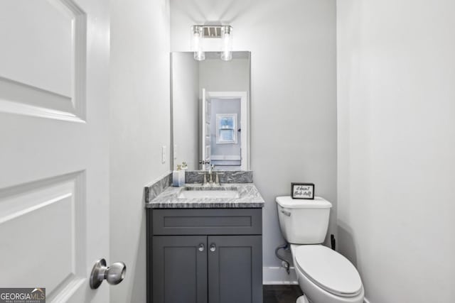 half bath with toilet, vanity, and baseboards