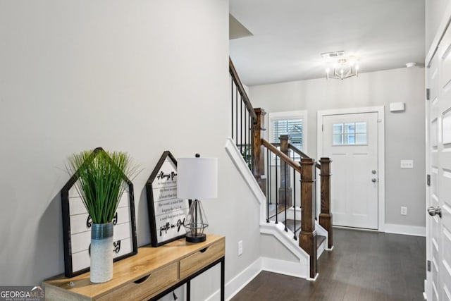 foyer entrance featuring dark wood-style floors, stairway, an inviting chandelier, and baseboards