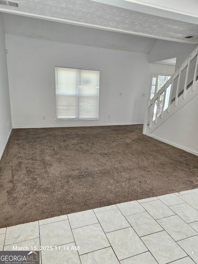 11187 Shannon Cir, Hampton, GA 30228 - tiled spare room with visible vents, baseboards, carpet floors, vaulted ceiling, and a textured ceiling
