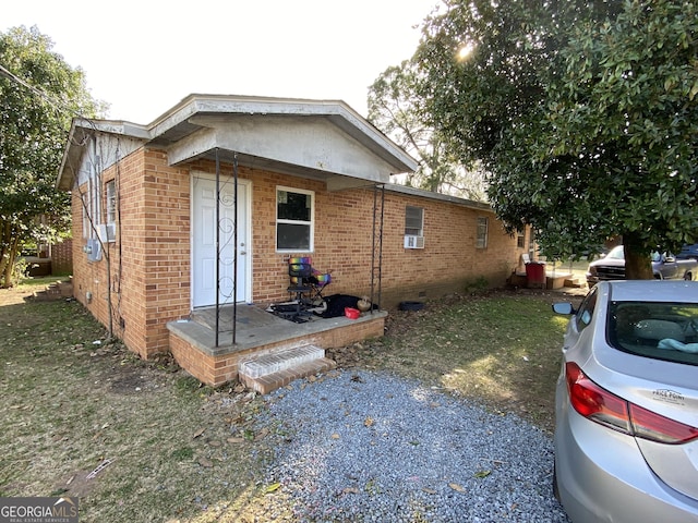 view of front of property featuring crawl space, brick siding, and cooling unit