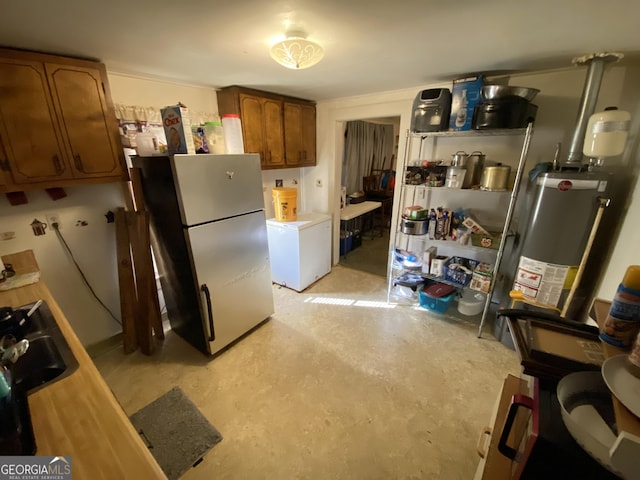 kitchen with light countertops, concrete flooring, water heater, freestanding refrigerator, and refrigerator