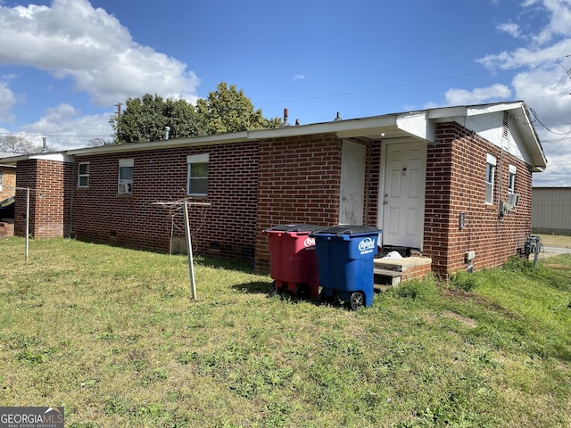 rear view of property with crawl space, a yard, and brick siding