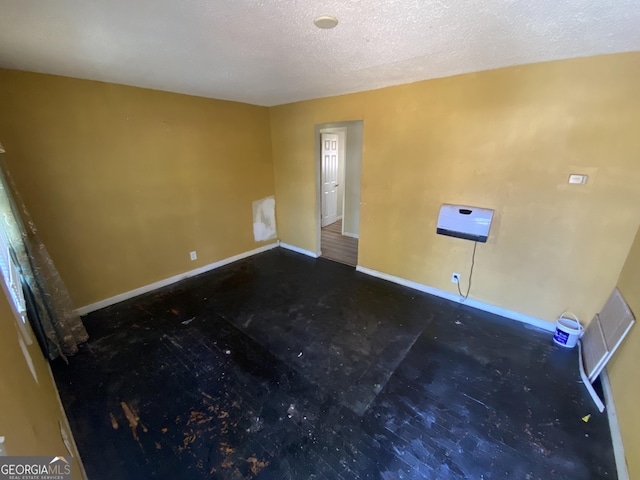 spare room with a textured ceiling and baseboards