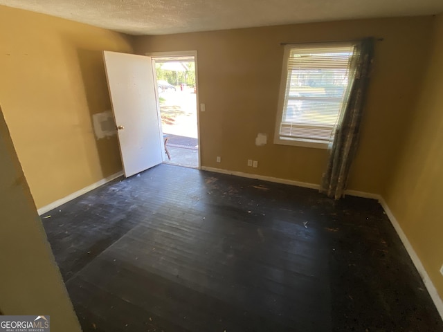 unfurnished room featuring a textured ceiling and baseboards