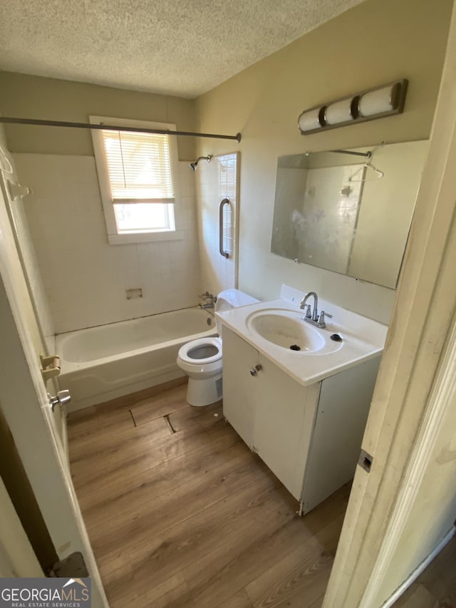 bathroom featuring toilet, a textured ceiling, wood finished floors, bathtub / shower combination, and vanity