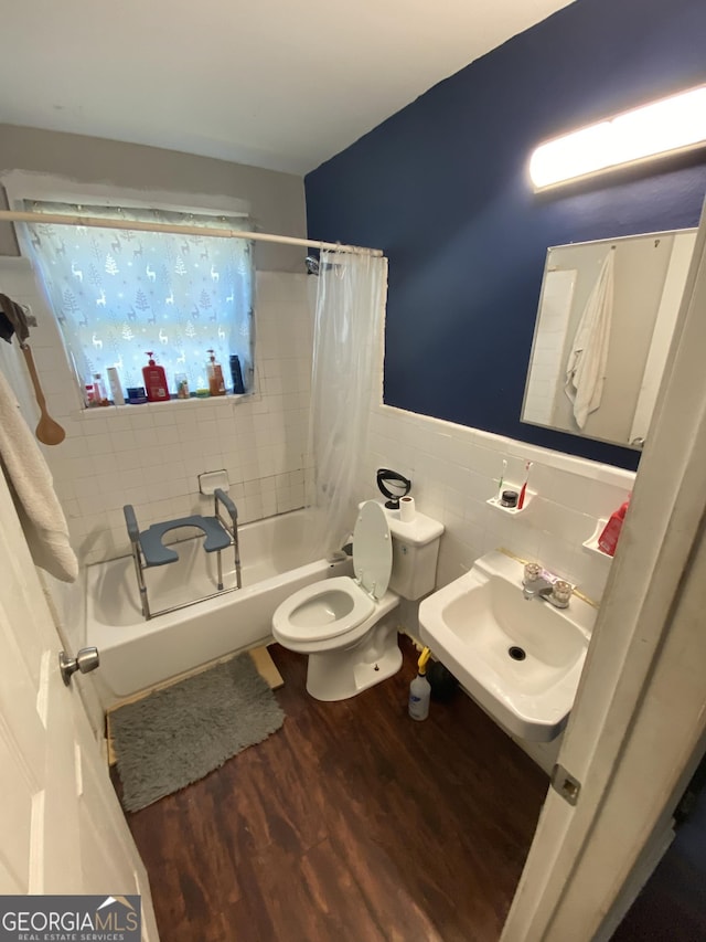 bathroom with toilet, shower / tub combo, wood finished floors, tile walls, and a sink