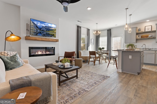 227 Ivey Ter Unit 36, Temple, GA 30179 - living area with light wood-type flooring, a chandelier, a glass covered fireplace, recessed lighting, and ceiling fan