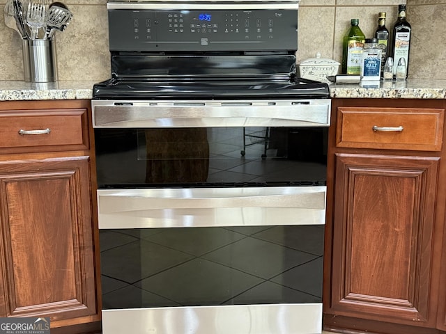 kitchen featuring brown cabinetry, electric stove, and light stone countertops