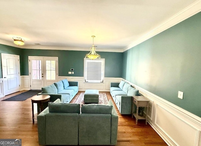 living area featuring french doors, wainscoting, dark wood-style flooring, and crown molding