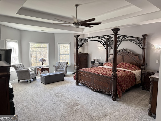 carpeted bedroom with multiple windows, a tray ceiling, and visible vents