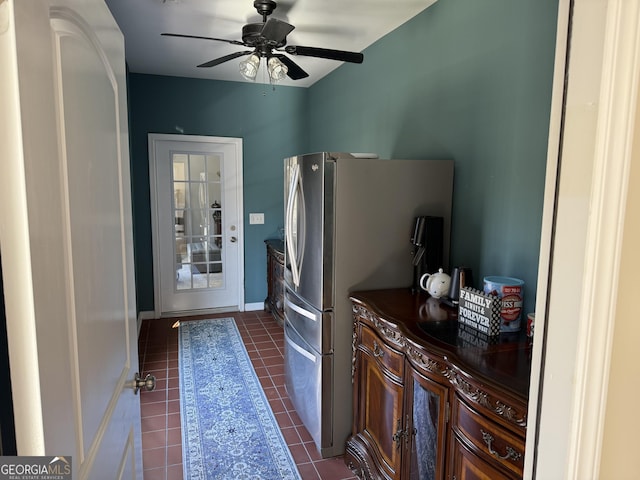 kitchen featuring dark countertops, dark tile patterned flooring, freestanding refrigerator, and ceiling fan